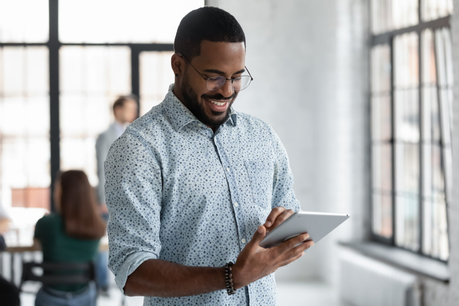 Happy Black male employee reading on digital device screen
